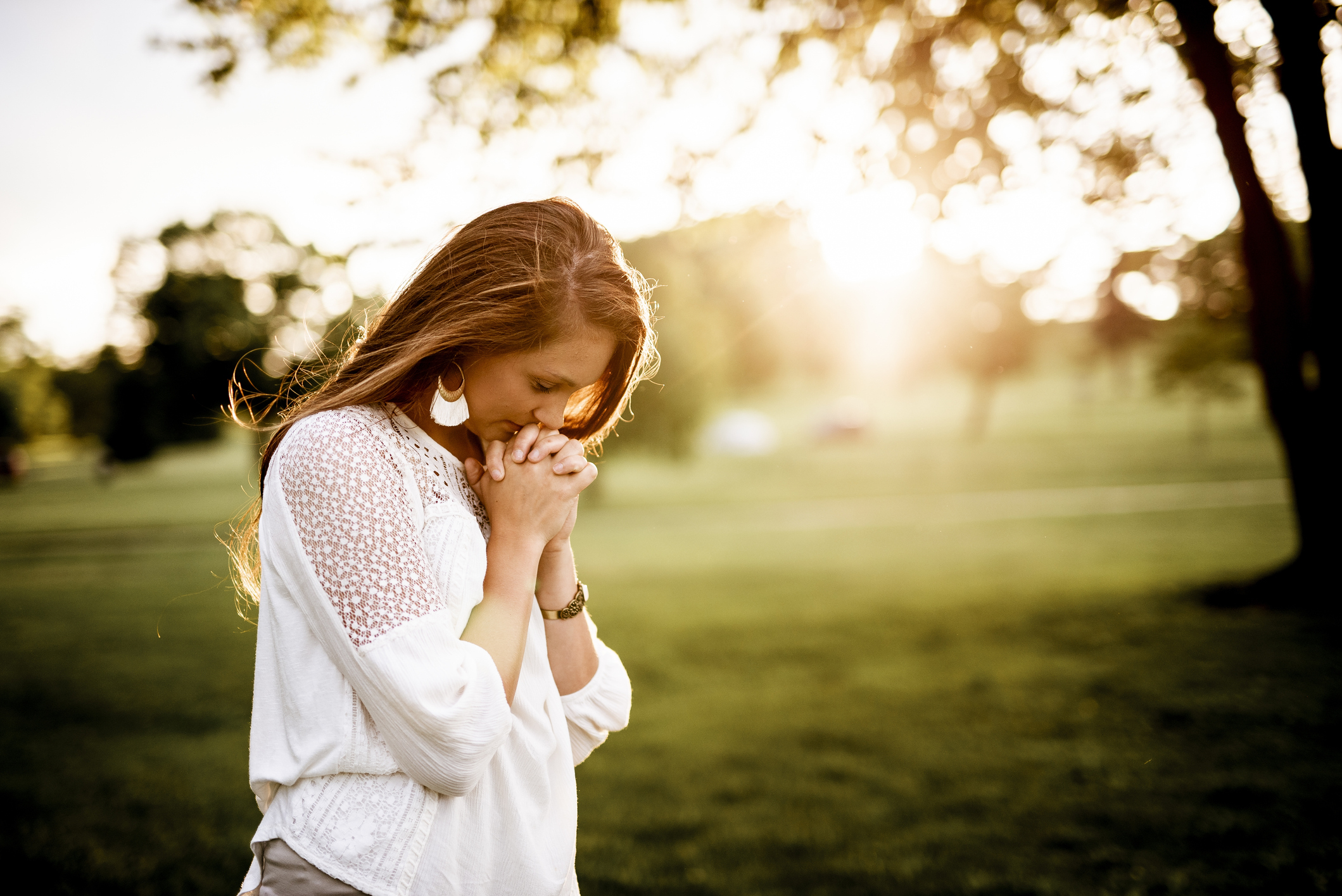 A closeup shot of a female praying with a blurred background