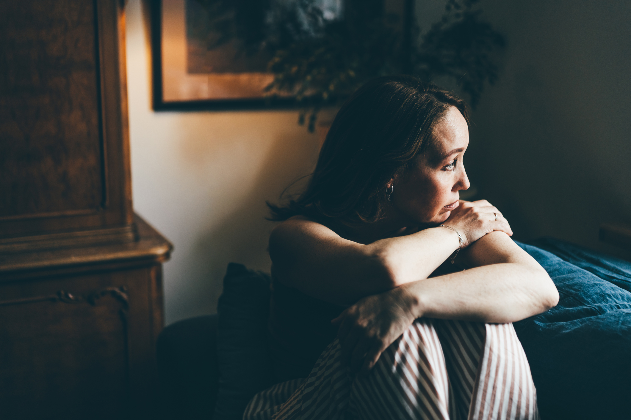 Suffering woman sitting on sofa at home.