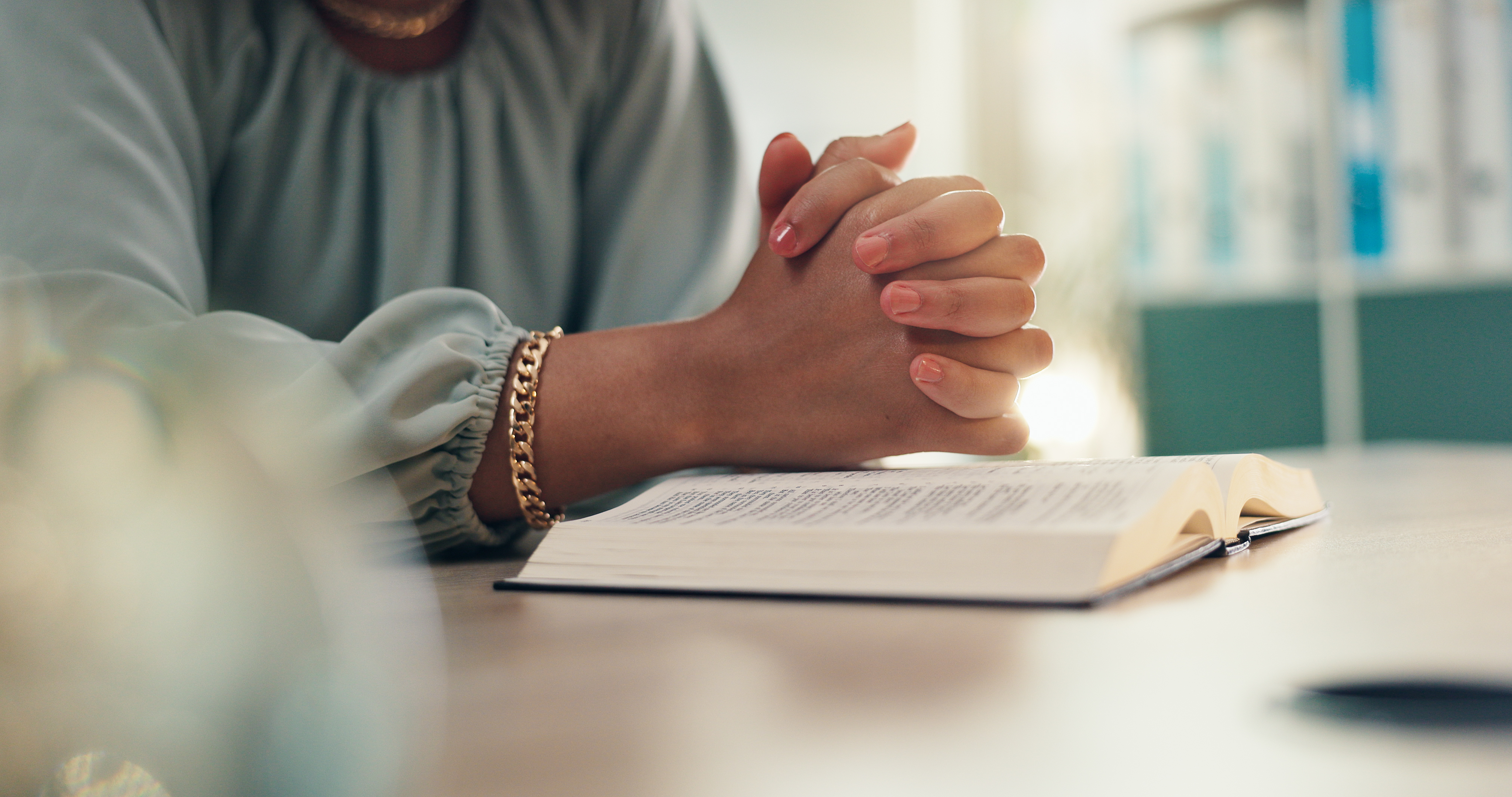 Hands, prayer and bible for religion in home with worship, peace and reading for spiritual guide. Person, Christian book and faith with reflection with scripture for connection to God at apartment