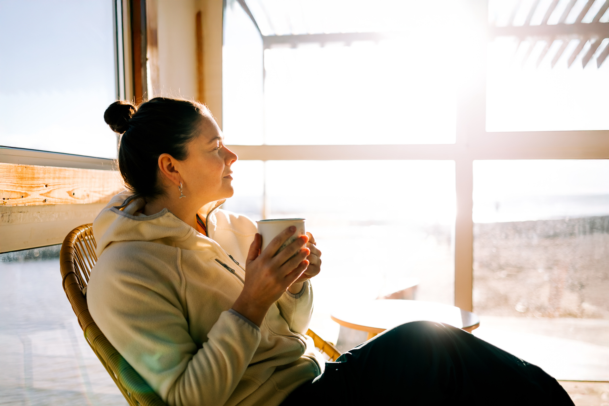 Serene woman relaxing with warm drink by sunny window