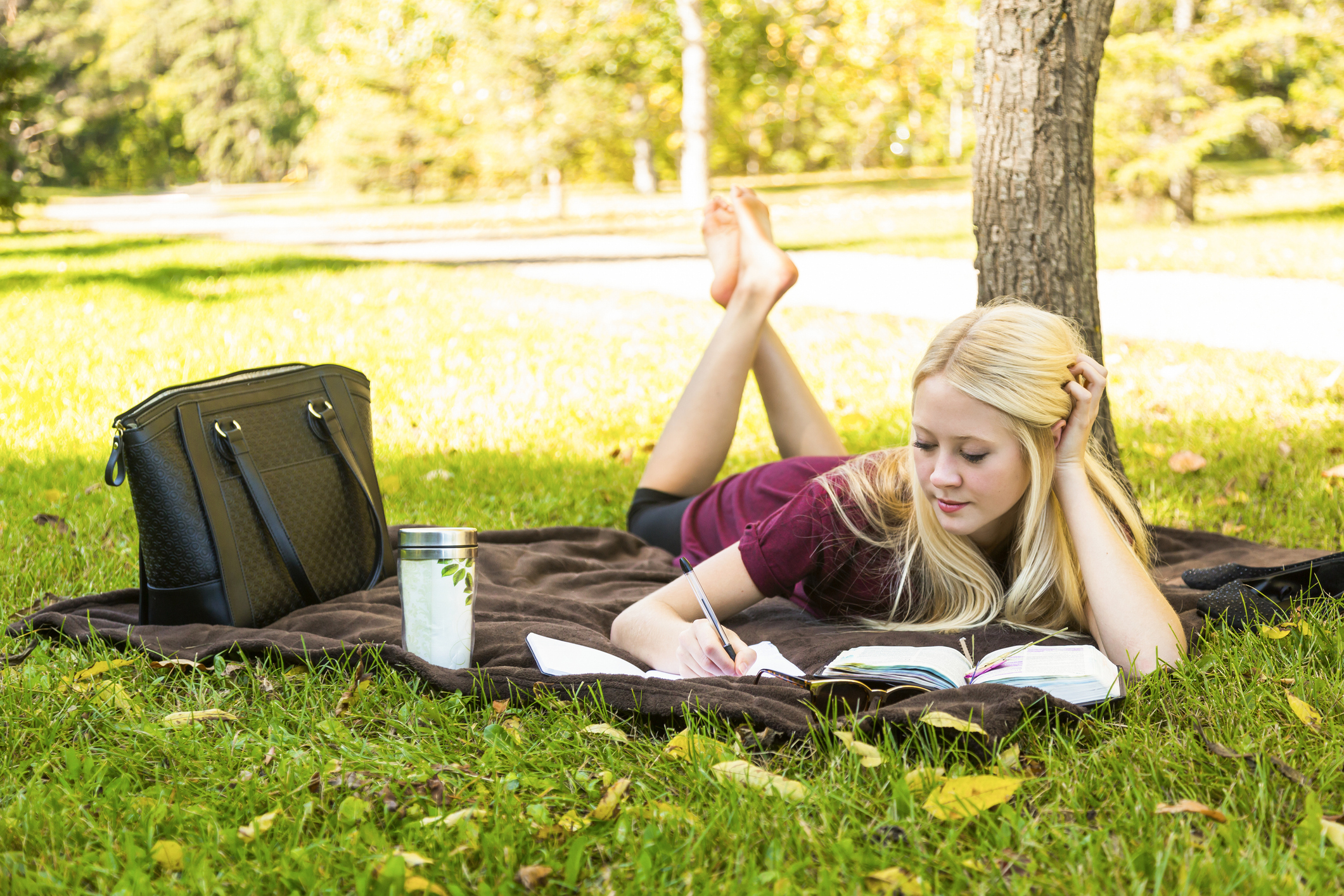 A young woman spending personal time in Bible study outdoors in a park in autumn