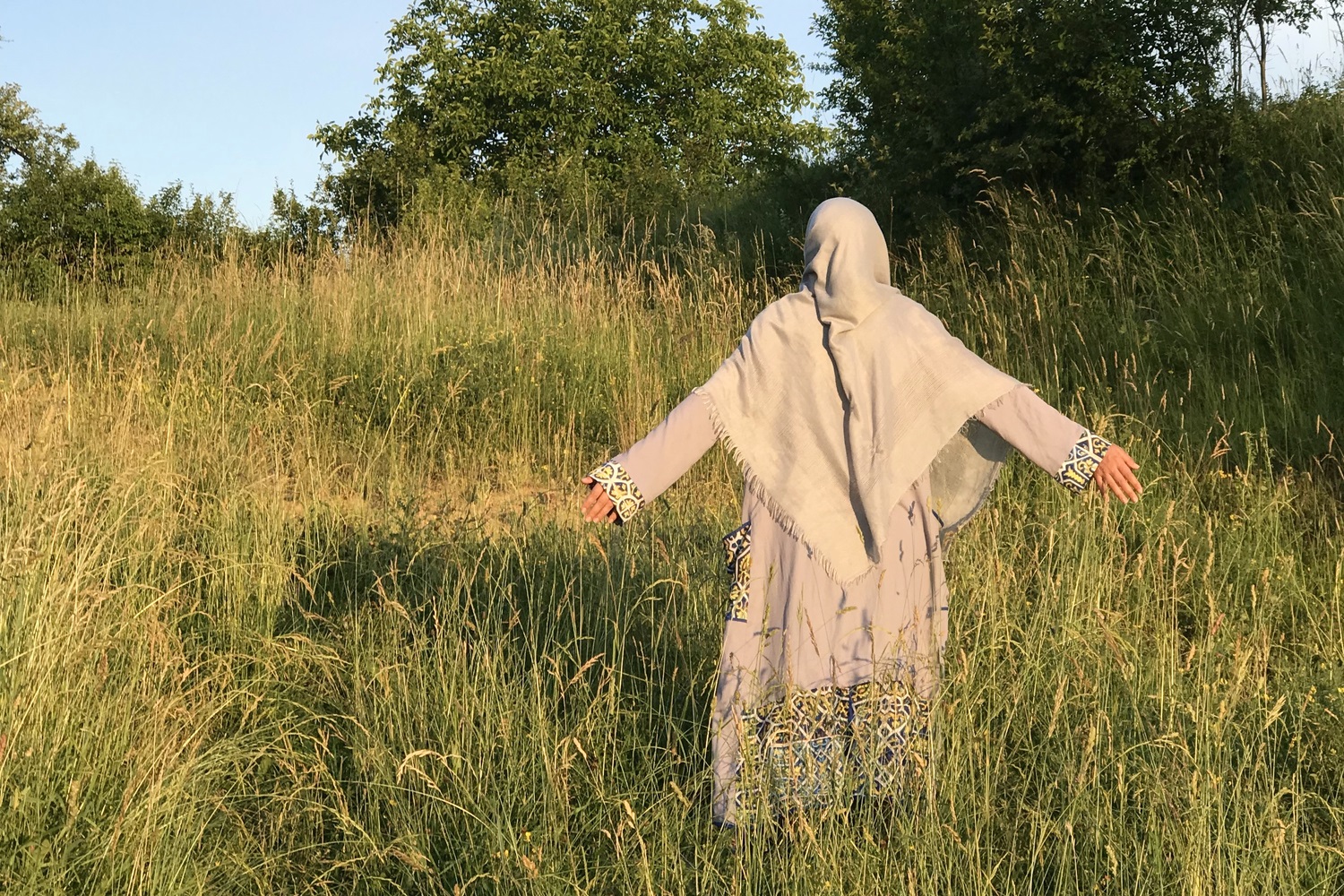 woman standing in a field with arms out